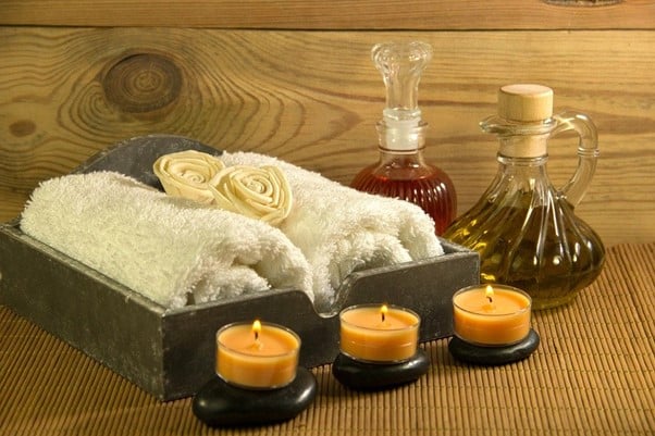Wellness box with rolled up towels, tea light candles and oils in glass containers