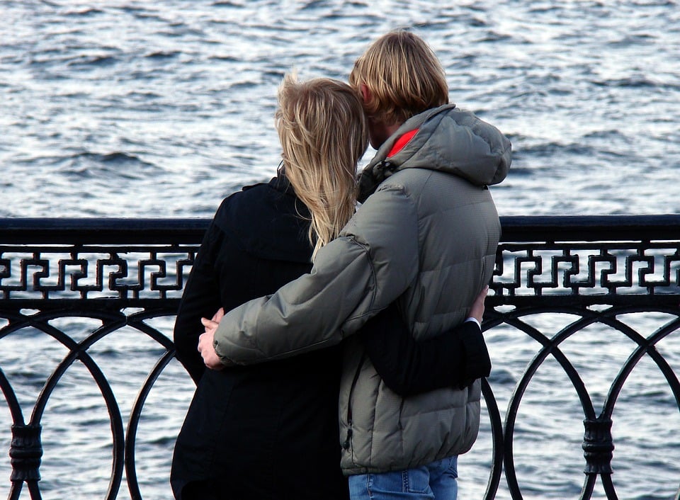 Man with arm around woman on a date overlooking the river bank