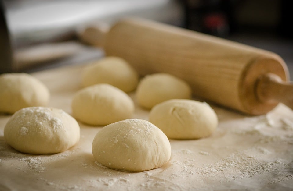 Dough balls and wooden rolling pin sat on kitchen side for baking biscuits