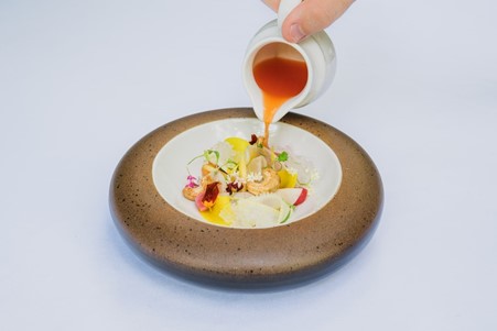 Person pouring sauce on fine dining dish
