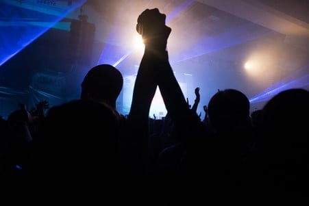 Silhouette of couple holding hands in the air at an indoor gig