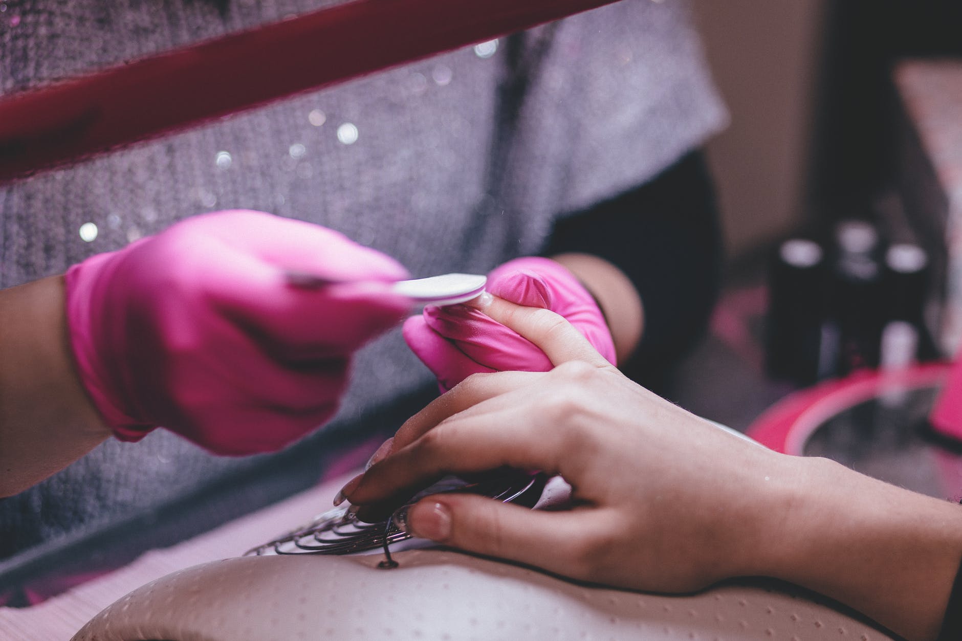 Woman with pink gloves giving manicure to a client