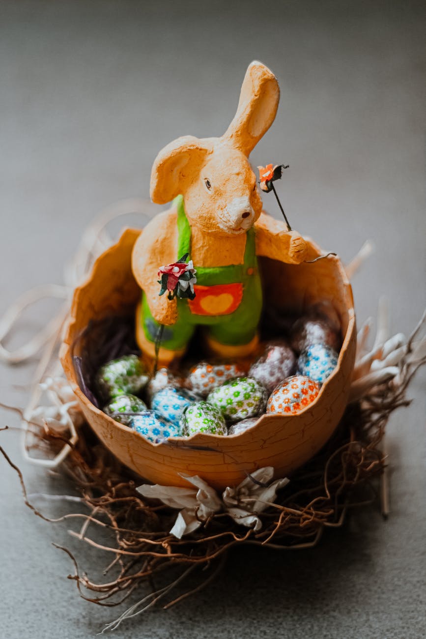 Bunny rabbit figure sat in egg shaped container with chocolate eggs