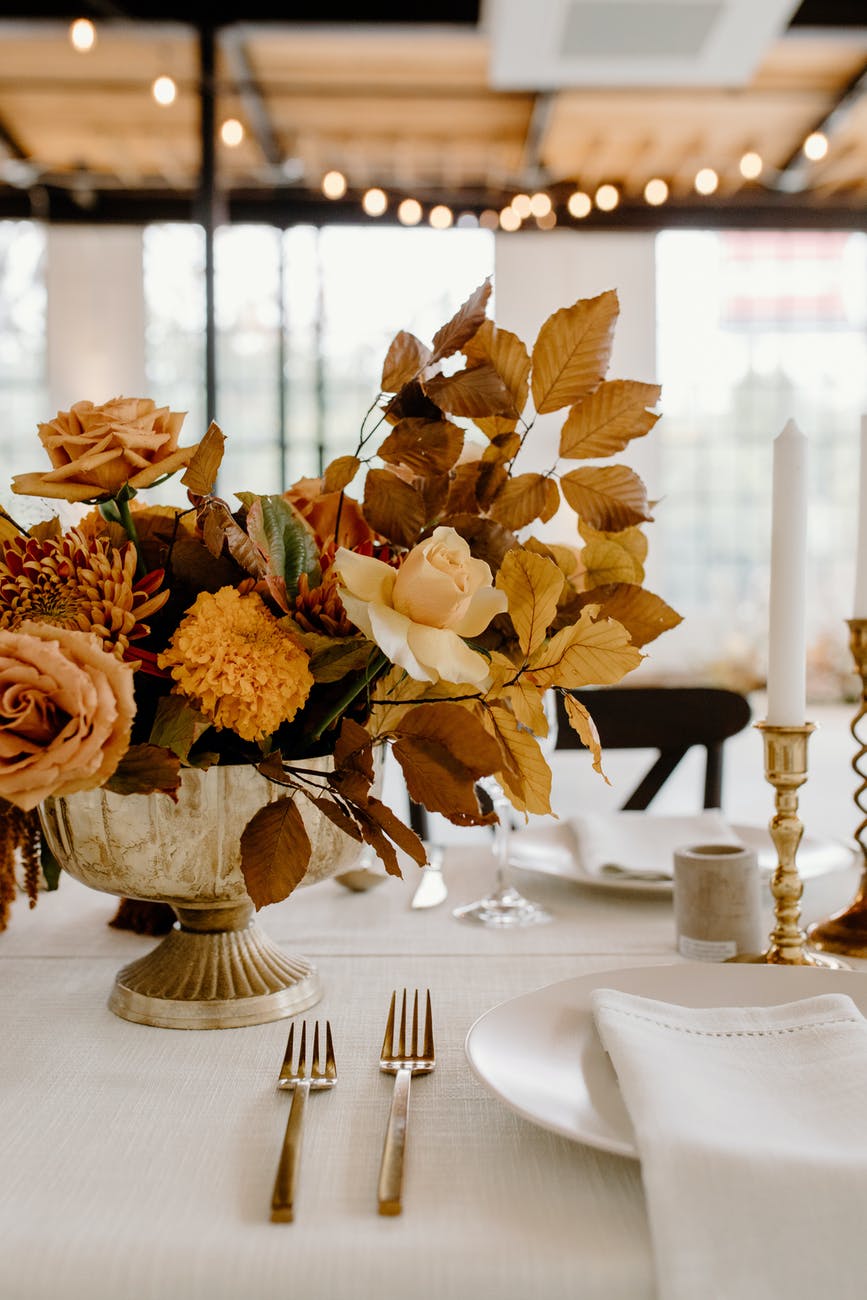 Wedding table with white cloth, dinnerware, a candle stick and vase of flowers