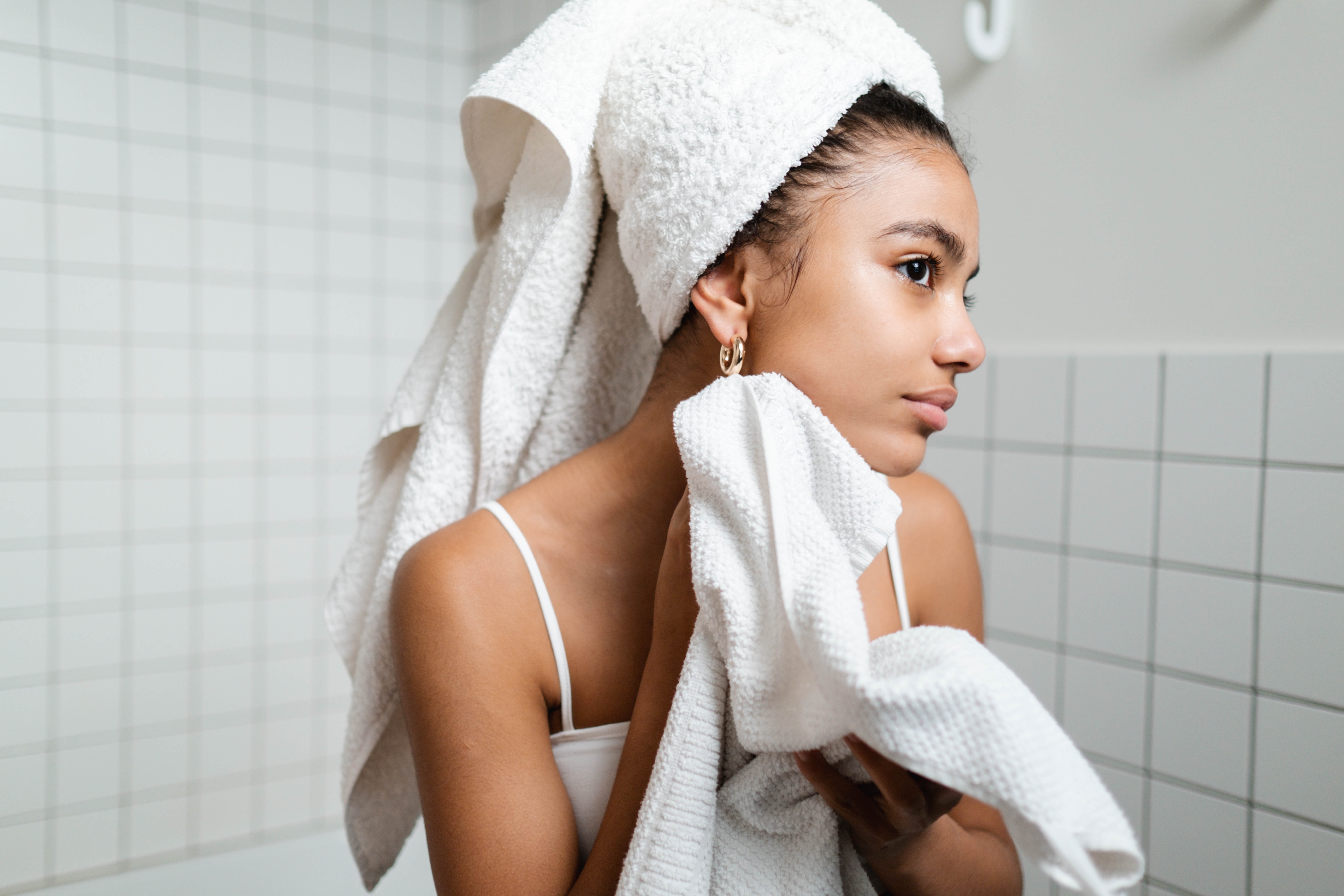 Woman with brown eyes staring into reflection with towel on head and body